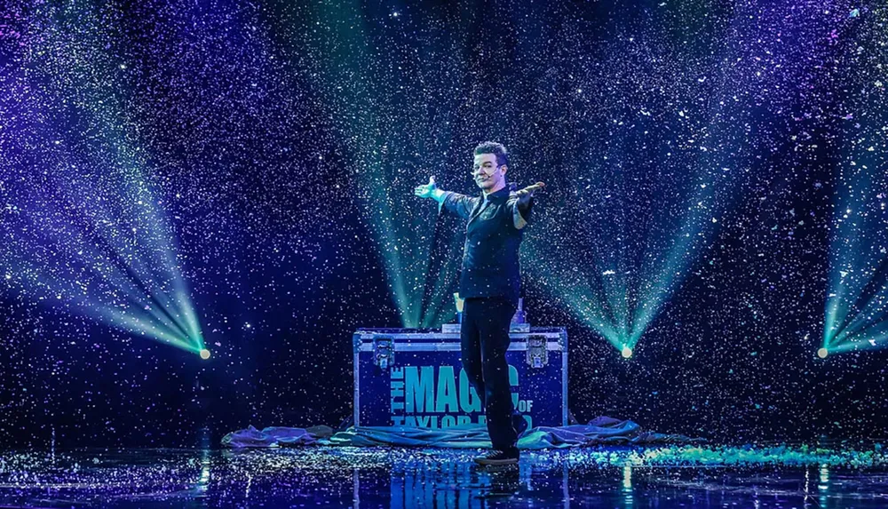 A magician is performing on stage surrounded by a shower of confetti and vibrant spotlights