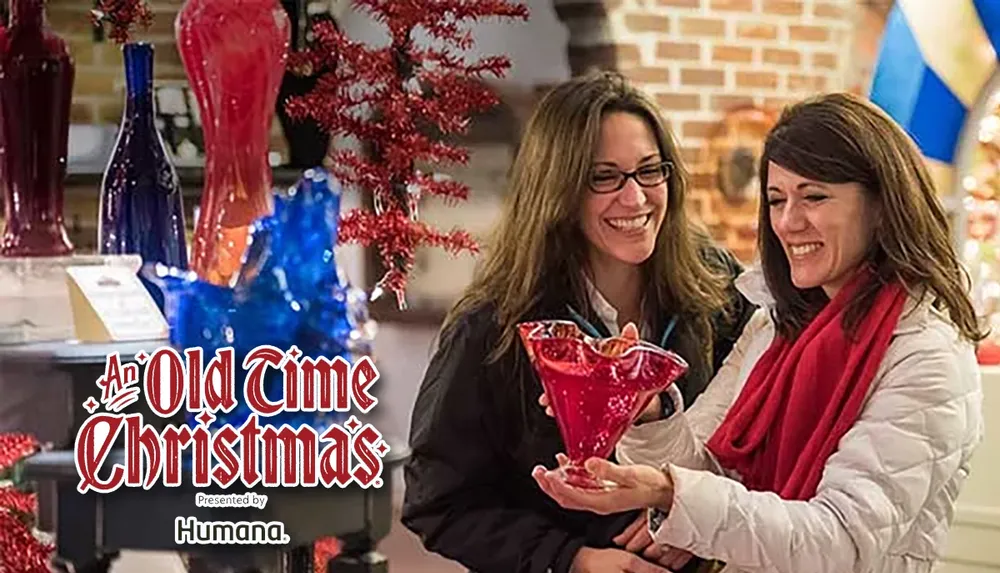 Two people are smiling while holding a red glass vase at an event called An Old Time Christmas presented by Humana