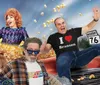 A group of cheerful people in colorful outfits are playfully posed with popcorn and a vintage car against a backdrop of a road sign for Missouri Route 76