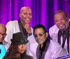 This is a digitally altered image featuring a montage of various people seemingly performers with a backdrop of purple stage curtains and spotlights