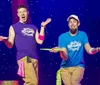 Two performers are on stage with surprised expressions holding spinning plates on sticks against a starry background