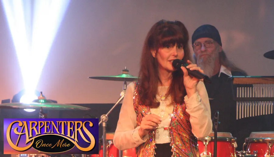 A woman is singing into a microphone on stage with a musician in the background, and the overlay text reads CARPENTERS Once More.