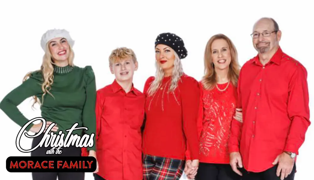 A family of five is posing together with adults and a child dressed in festive red and green clothing against a white background