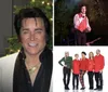 A person resembling Elvis Presley stands in front of a Christmas tree with a backdrop that reads Elvis Live
