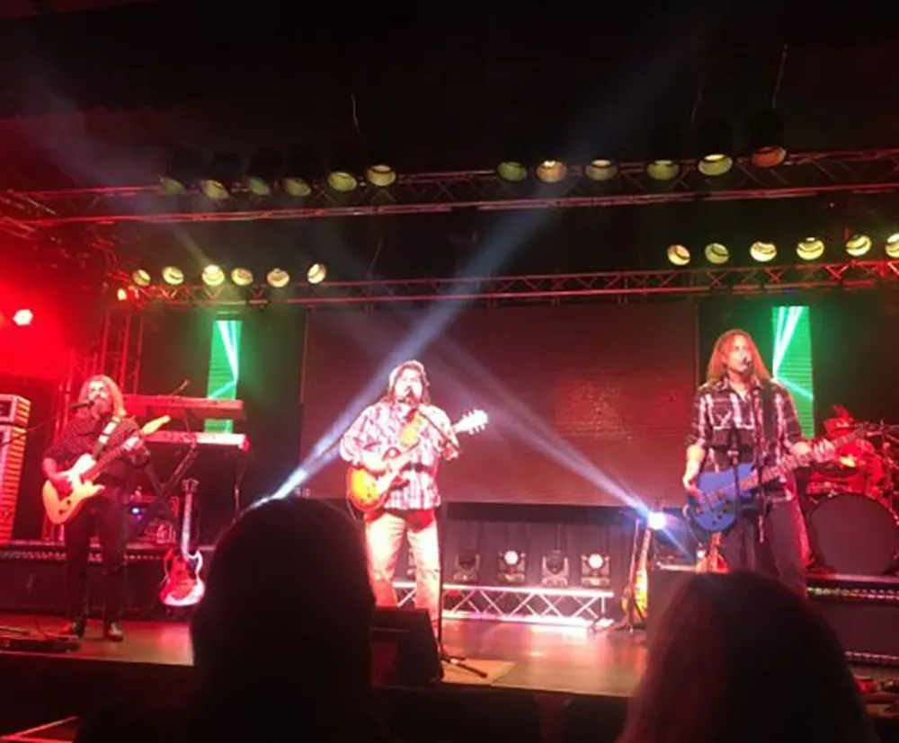 A band is performing live on stage under colorful stage lighting