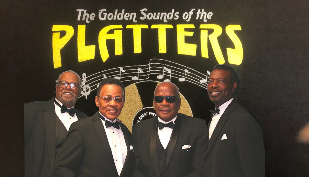 Four men in tuxedos stand in front of a backdrop featuring the phrase The Golden Sounds of the Platters
