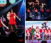A group of performers in festive red outfits are energetically singing and dancing on stage with a Christmas-themed backdrop