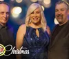 Three people are smiling in a festive bokeh-lit setting with Christmas and a logo for Absolutely Country Definitely Gospel shown in the image