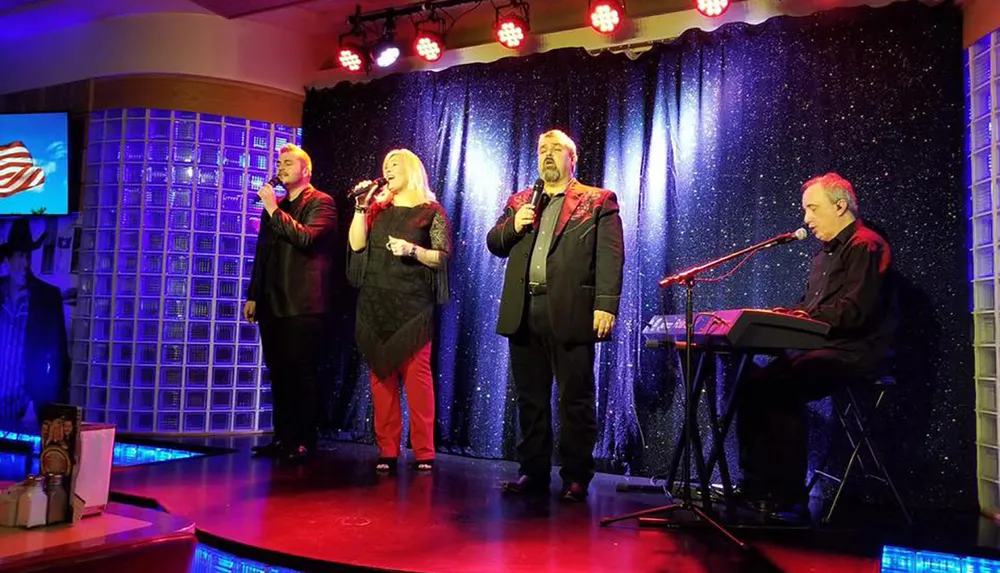 Three singers are performing on stage while a musician accompanies them on a keyboard against a backdrop of a starry curtain and red stage lights