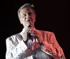 The image is a collage of five photographs showing a smiling man in various outfits including a white shirt a patterned jacket sunglasses and performing on stage with a microphone