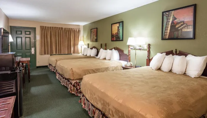The image shows a tidy hotel room with two large beds traditional furnishings and art on the walls