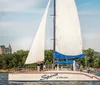 A group of people enjoys a sunny day sailing on a boat named Spirit of America with a backdrop of a lakeshore and buildings