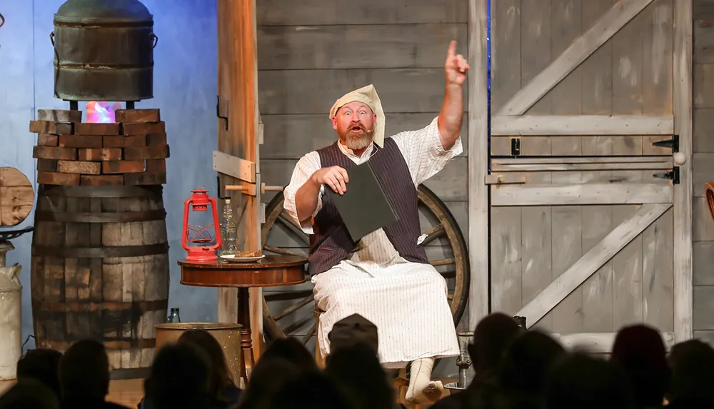 A performer dressed in period costume is enthusiastically addressing an audience likely narrating a story or acting in a play in a rustic historically styled setting