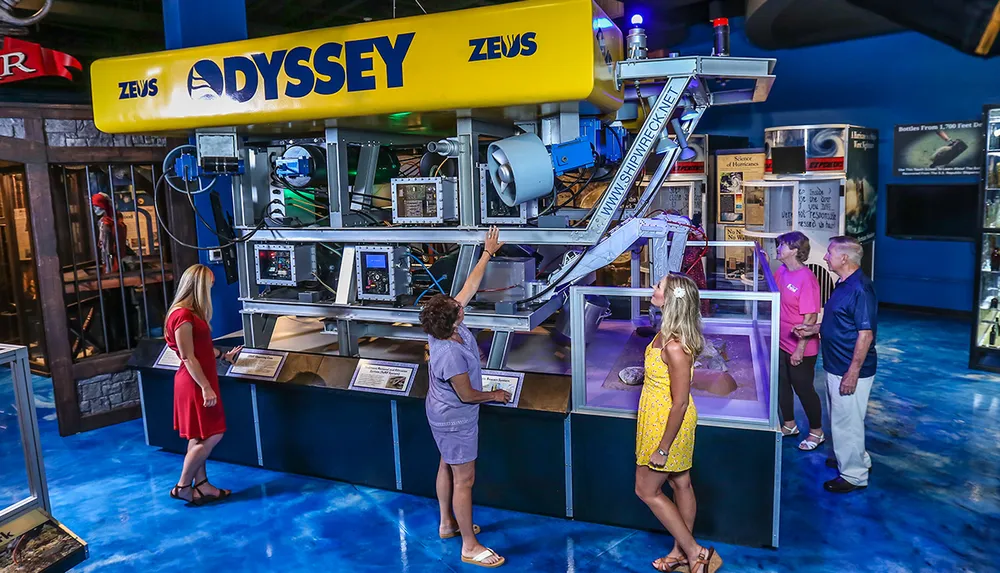 Visitors are examining a large underwater remotely operated vehicle ROV named ZEUS from Odyssey on display at a museum or exhibition