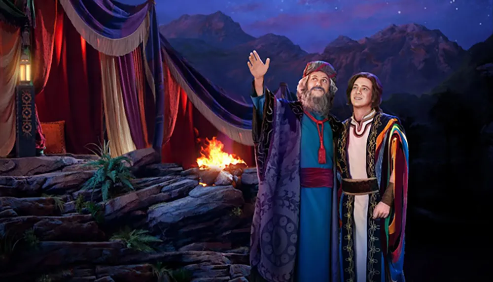 The image depicts two characters likely from a biblical or historical setting in colorful robes looking skyward with a campfire and dramatic mountainous landscape in the background