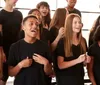 A group of joyful students is singing together with some placing their hands over their hearts